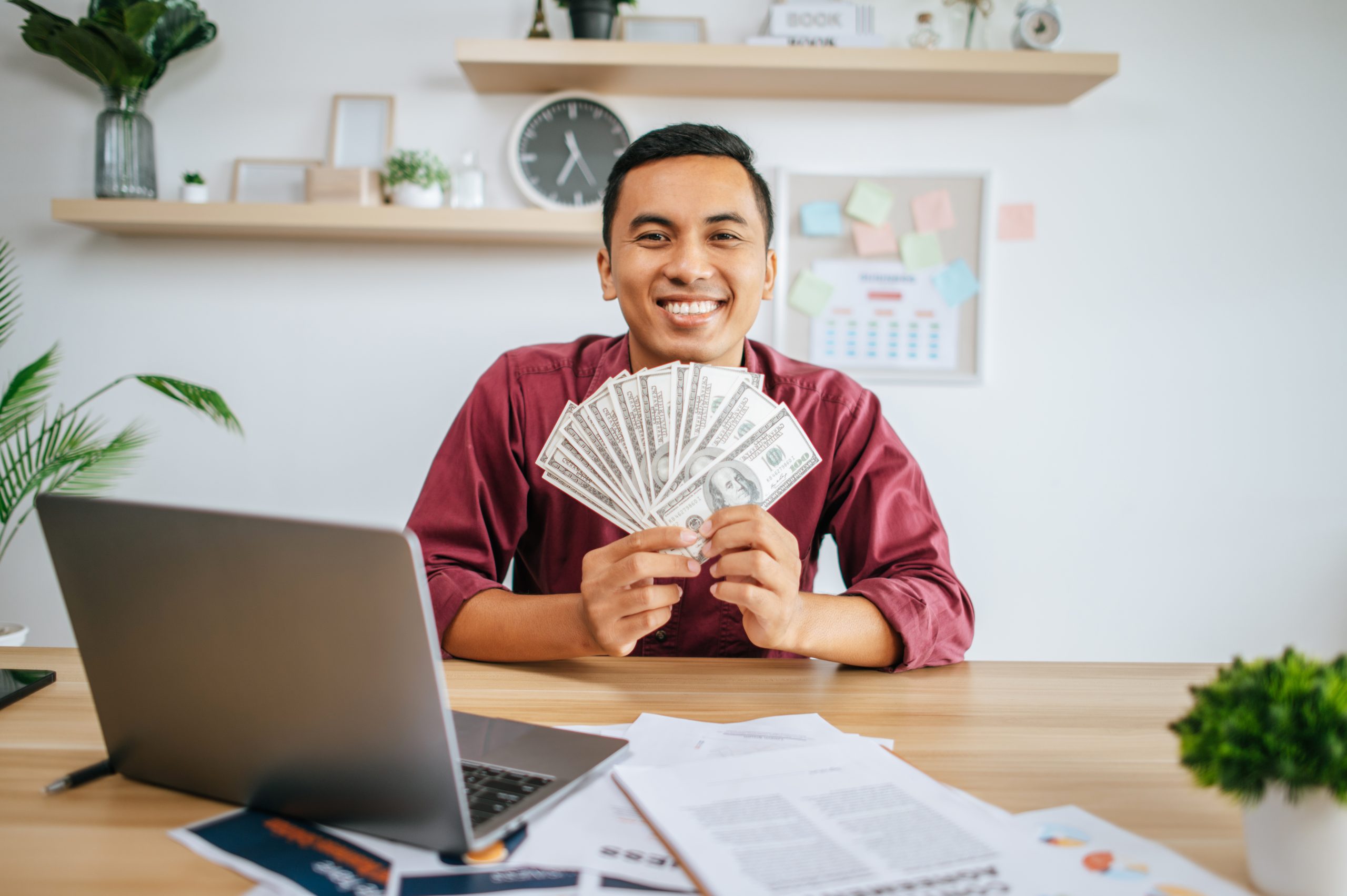a man working in an office and holding money. Micro Loans Canada